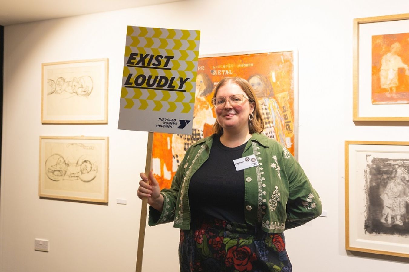 Emily Mann holding up a sign that reads 'exist loudly'