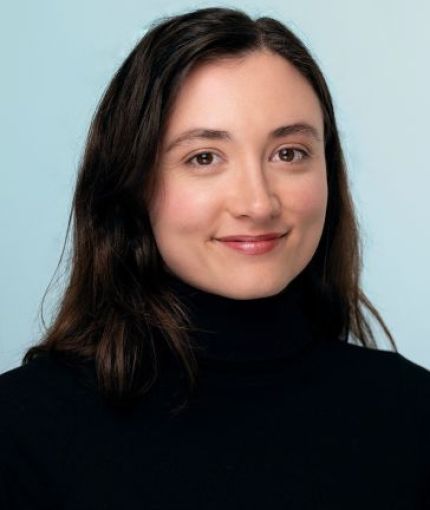 female-presenting, brown hair, brown eyes and a black turtleneck 