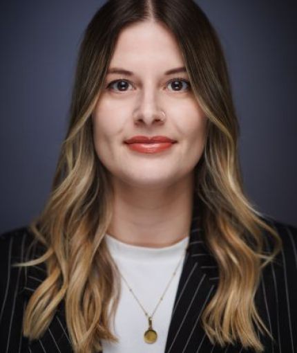 A portrait of Leah with short blonde hair wearing a pinstripe blazer