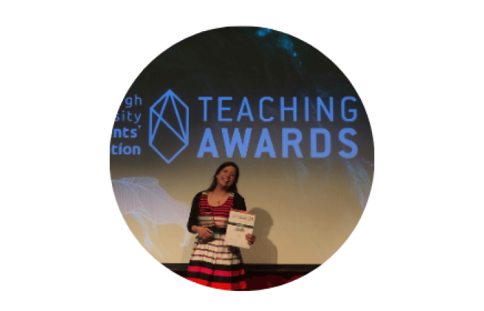 Photo of Claire on stage at the teaching awards, holding her award certificate 