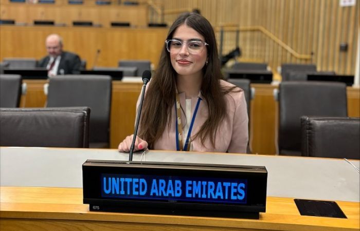 Photo of Jana Alrahami at the UN, with a sign in front of her labelled 'United Arab Emirates'