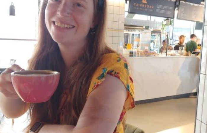 Picture of a young woman holding a cup of coffee. 