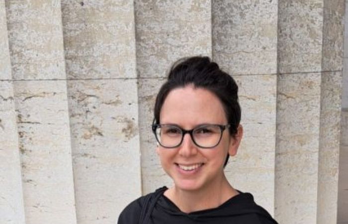 Woman sitting in front of a column.
