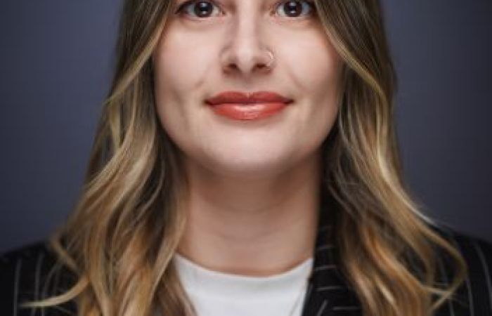 A portrait of Leah with short blonde hair wearing a pinstripe blazer