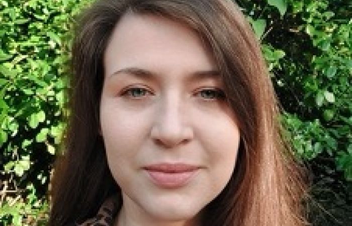 Photograph shows a white woman in her mid-30s with long brown hair.