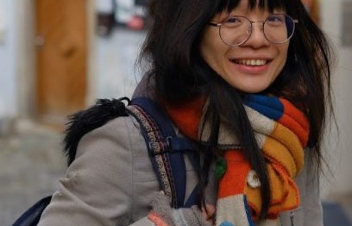 This is me traveling to Prague in the year 2020 before the pandemic, with my grey coat and a colourful scarf.
