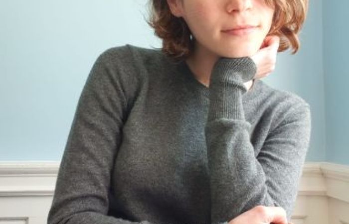 The image depicts Nitzan, photographed against a plan background, looking straight to the camera.