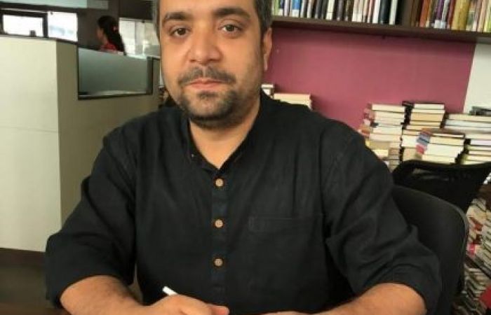 A person wearing black shirt sitting around books